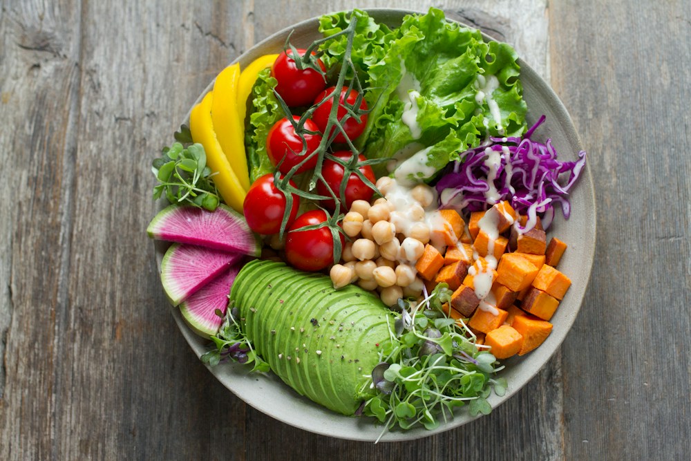 A colourful bowl of fresh vegetables, chickpeas, and greens